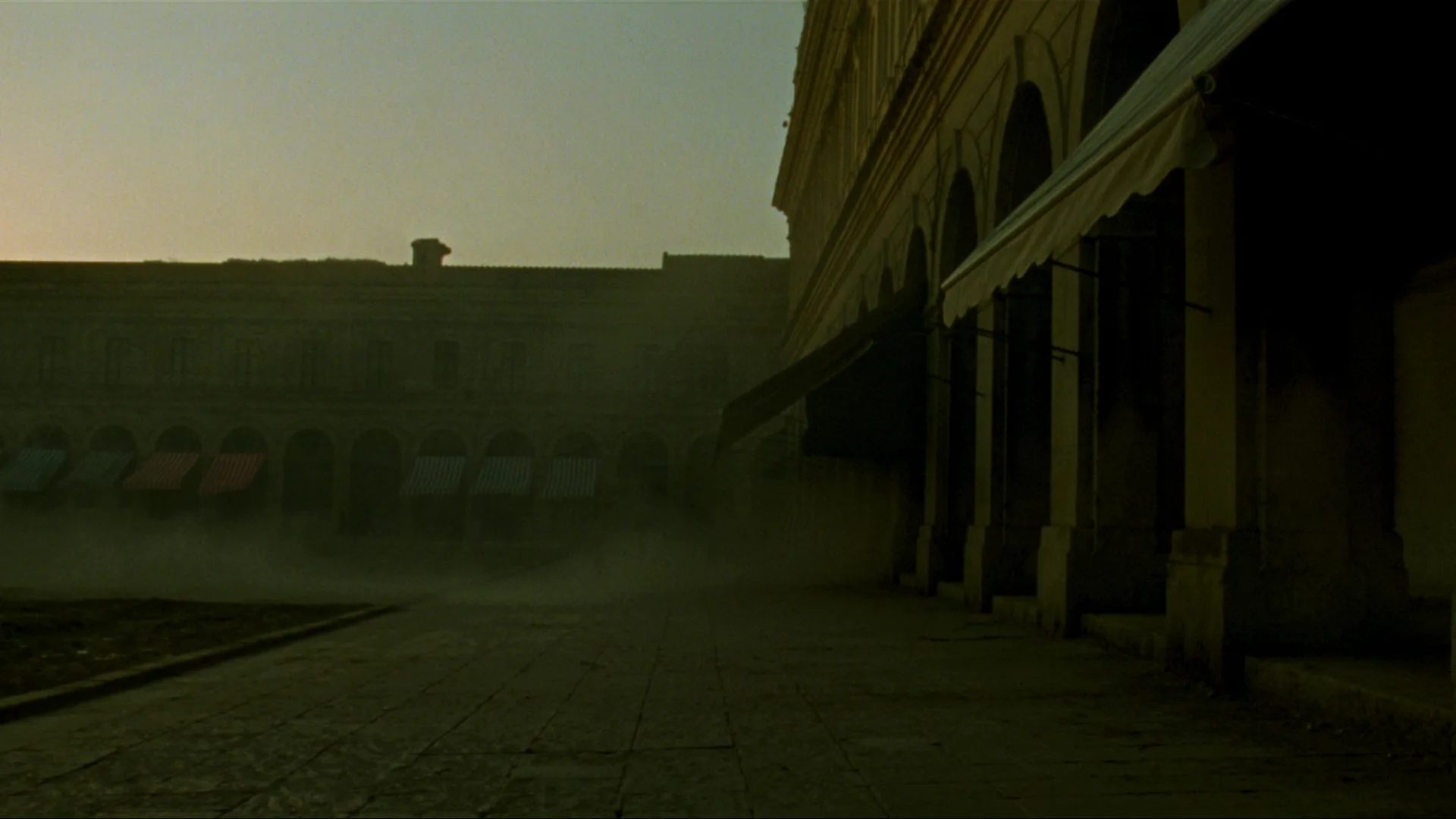 Dawn over an empty Mediterranean market square, stone arcades and striped awnings in golden light